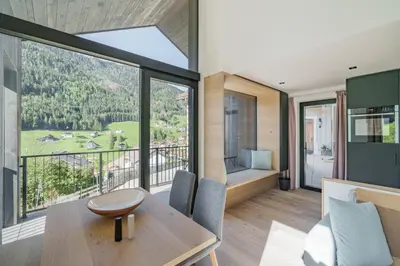 a living room with a table and chairs and a large window at Villa Rames in Ortisei