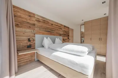 a bedroom with a white bed with a wooden wall at Villa Rames in Ortisei