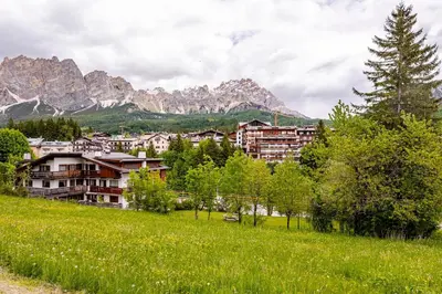 a town in a field with mountains in the background at Appartamento Crignes in Cortina dʼAmpezzo