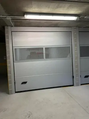 a garage with a white garage door in a parking lot at Appartamento Crignes in Cortina dʼAmpezzo