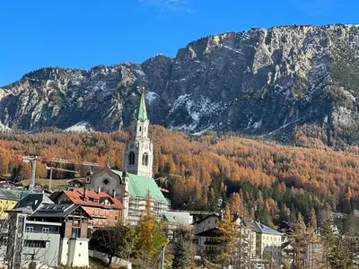 a church with a steeple in front of a mountain at Appartamento Crignes in Cortina dʼAmpezzo