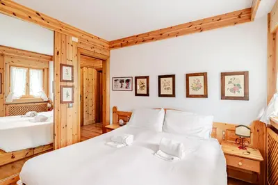 a bedroom with a large white bed and a mirror at Appartamento Crignes in Cortina dʼAmpezzo