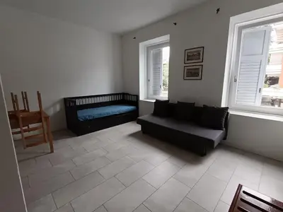 a living room with a couch and two windows at Apartaments and Rooms Claudia Augusta in Bolzano