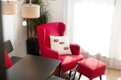 a living room with a red chair and a table at Casa Maria Beatrice in Mühlbach