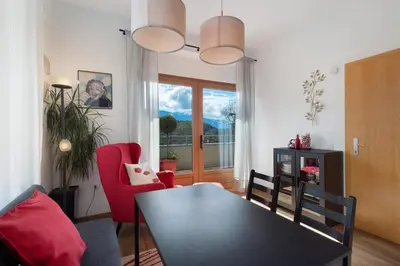 a living room with a table and red chairs at Casa Maria Beatrice in Mühlbach