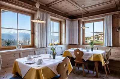 a dining room with two tables and large windows at Hotel Landgasthof Lärchenwald in Collepietra