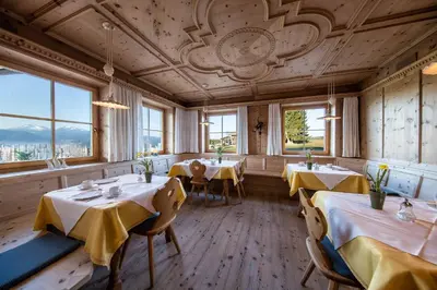 a restaurant with tables and chairs and windows at Hotel Landgasthof Lärchenwald in Collepietra