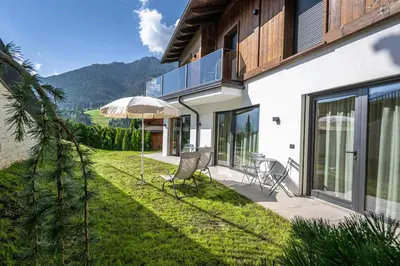 a house with a patio with an umbrella and chairs at Chalet Berna in Ortisei