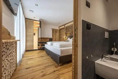a bedroom with a bed and a sink and a tub at Chalet Berna in Ortisei