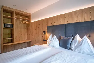 a bedroom with a large white bed with wooden walls at Apartments LaBar in Ortisei
