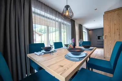 a dining room with a wooden table and blue chairs at Apartments LaBar in Ortisei