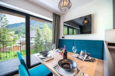 a dining room with a table and chairs and a large window at Apartments LaBar in Ortisei