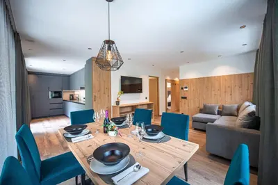 a dining room and living room with a wooden table and blue chairs at Apartments LaBar in Ortisei