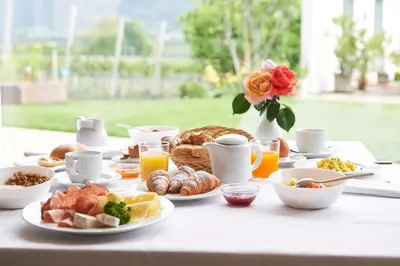 a table topped with plates of breakfast foods and orange juice at Hotel Gantkofel in Andrian