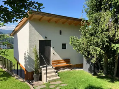 a house with a bench on the side of it at Das Baumhaus in Fiè