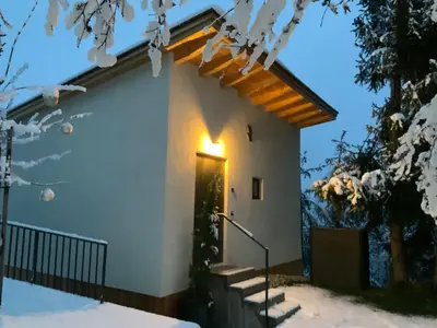 a house in the snow with a light on the door at Das Baumhaus in Fiè