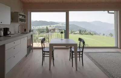 a kitchen with a table and chairs and a large window at Das Baumhaus in Fiè