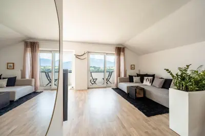 a white living room with a couch and a kitchen at Villa Maria Boutique Apartment St Pauls in Appiano sulla Strada del Vino