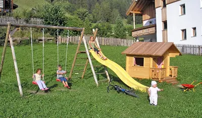a group of children playing on a swing set in a yard at Agriturismo Tolpei in La Valle