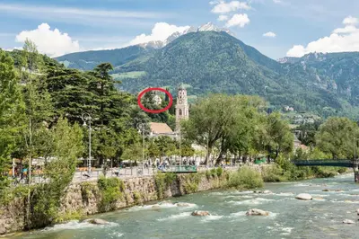 a building next to a river with a mountain at Villa Hochland in Merano