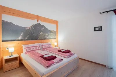 a bedroom with a bed with pink pillows and a painting at B&B Agriturismo Cèsa Ciasates in Canazei