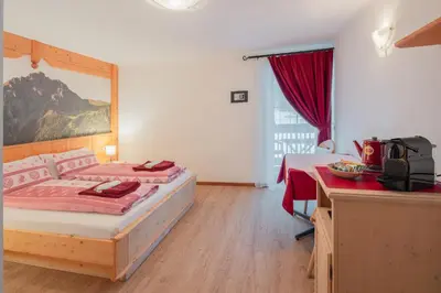 a hotel room with a bed and a desk with a desk at B&B Agriturismo Cèsa Ciasates in Canazei