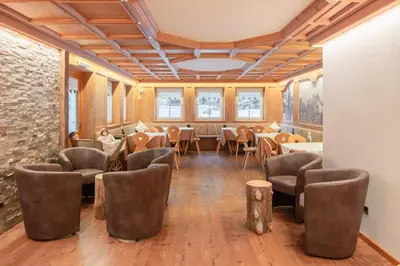 a room with chairs and tables and a brick wall at B&B Agriturismo Cèsa Ciasates in Canazei