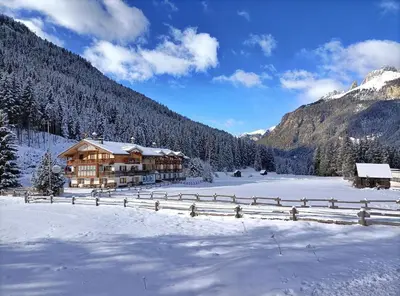 a lodge in the snow with a snow covered field at B&B Agriturismo Cèsa Ciasates in Canazei