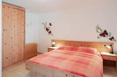 a bedroom with a bed and two wooden cabinets at Appartamenti Agriturismo Cèsa Ciasates in Canazei