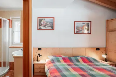a bedroom with a bed and a bathroom with a sink at Appartamenti Agriturismo Cèsa Ciasates in Canazei