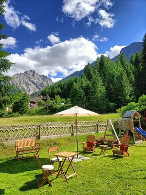 a group of picnic tables with an umbrella and a playground at Appartamenti Agriturismo Cèsa Ciasates in Canazei