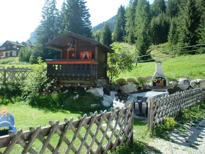 a small house in a yard with a wooden fence at Appartamenti Agriturismo Cèsa Ciasates in Canazei