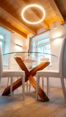a glass dining room table with two white chairs at Appartamento Vale e Schena Cortina D'Ampezzo in San Vito di Cadore
