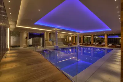 a swimming pool with blue lighting in a building at Hotel Aaritz in Selva di Val Gardena
