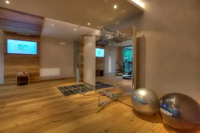 a living room with a large mirror and a gym at Hotel Aaritz in Selva di Val Gardena