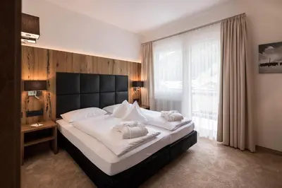 a bedroom with a large bed and a large window at Hotel Aaritz in Selva di Val Gardena