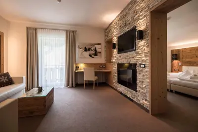 a living room with a stone wall with a fireplace at Hotel Aaritz in Selva di Val Gardena