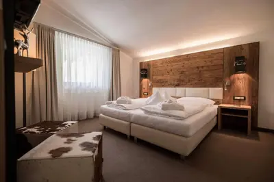 a hotel room with two beds and a window at Hotel Aaritz in Selva di Val Gardena