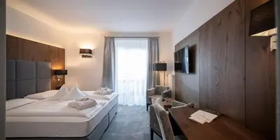 a hotel room with two beds and a desk at Hotel Aaritz in Selva di Val Gardena
