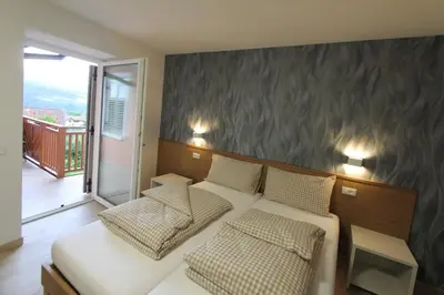 a bedroom with a bed and two chairs and a balcony at Affittacamere Mercedes in Romallo