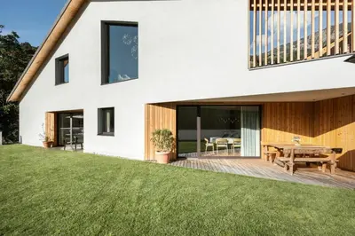 a house with a deck and a table on a lawn at Chalet Samont in Laion