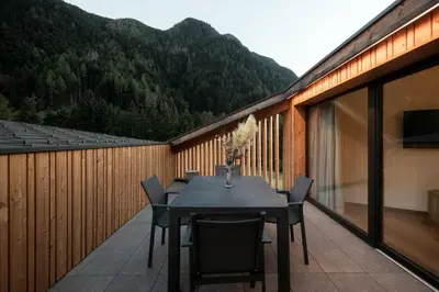 a black table and chairs on a balcony with mountains at Chalet Samont in Laion