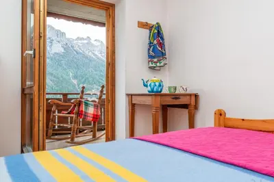 a bedroom with a bed and a table and a window at Sport & natura in Trentino! in Vigo di Fassa