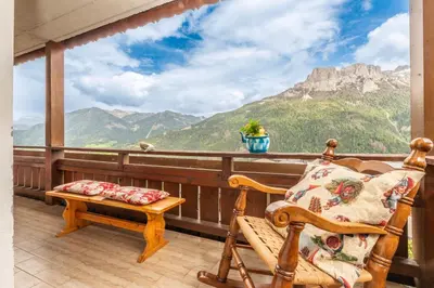 a balcony with a chair and a view of mountains at Sport & natura in Trentino! in Vigo di Fassa