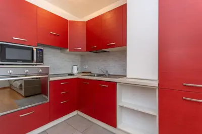 a kitchen with red cabinets and a microwave at Residenza Latemar in Moena