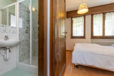 a bathroom with a shower and a sink and a bed at Residenza Latemar in Moena
