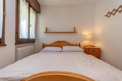 a bedroom with a large white bed and a window at Residenza Latemar in Moena