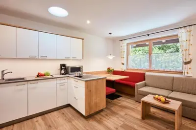 a kitchen and living room with a couch and a table at Ferienwohnung am Kernhof - Neues Apartment in ruhiger Lage mitten in der Natur - ideal für Paare, Familien, Gäste mit Hunden in Fiumes