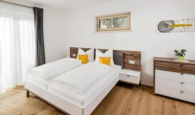 a white bedroom with a white bed with yellow pillows at Appartement Irene in Caldaro