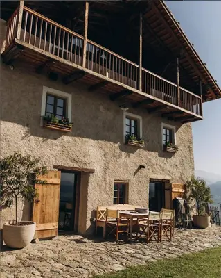 a house with a table and chairs in front of it at Felder Alpin Lodge in Villandro